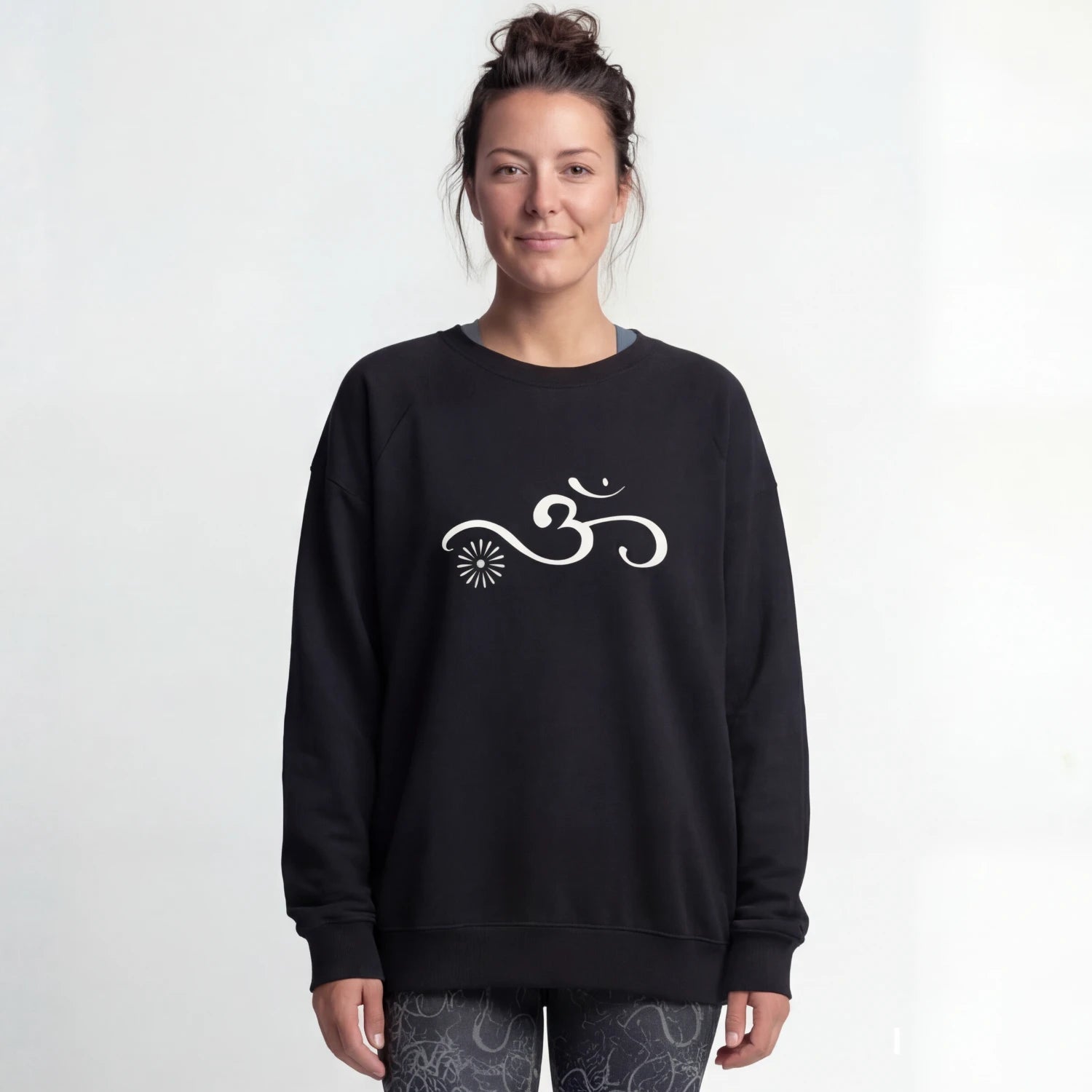 A person wearing a black yoga sweater with an Om symbol