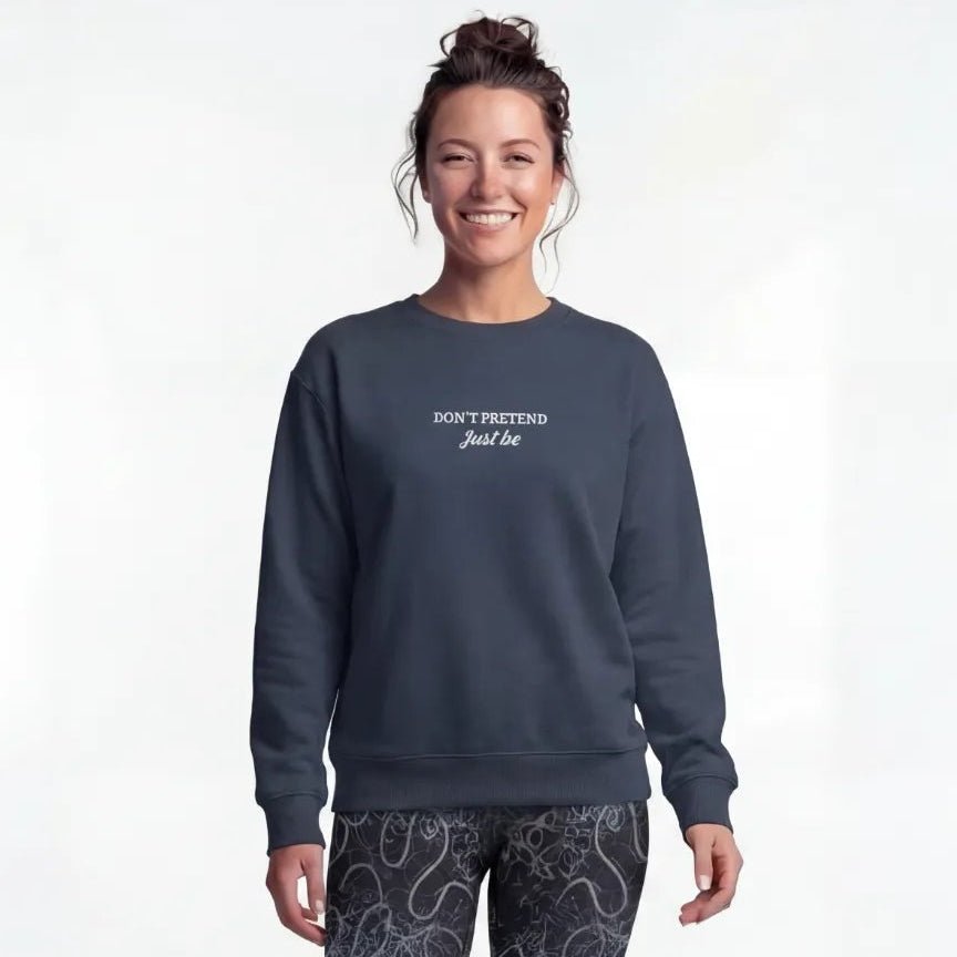 A person wearing a French navy yoga sweater with the text “Don’t pretend, just be